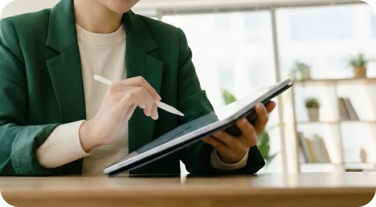 Una mujer haciendo su firma manuscrita en una tablet usando un lápiz digital blanco.