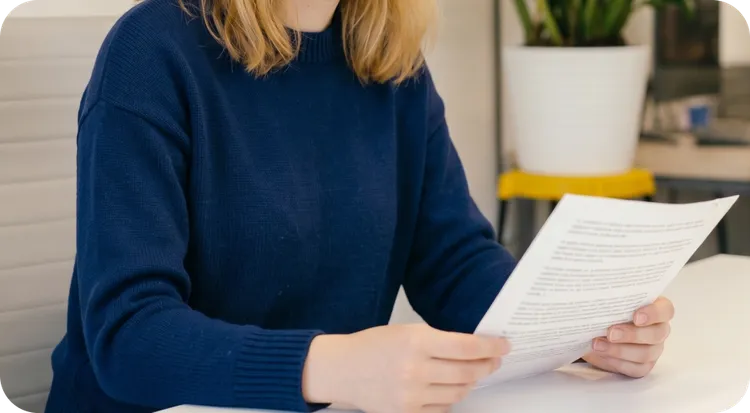 Mujer sosteniendo y leyendo un acuerdo de confidencialidad.