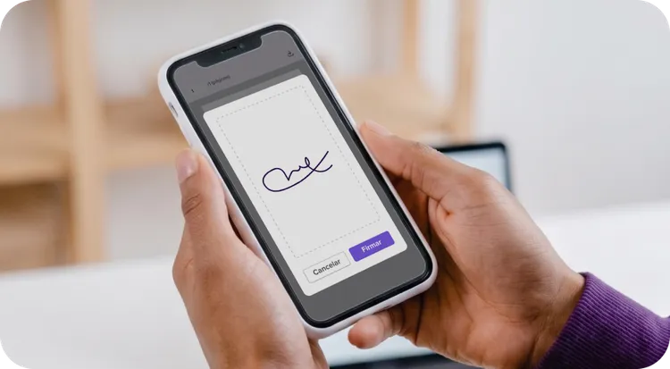 Person digitally signing on the screen of a mobile phone held with both hands.