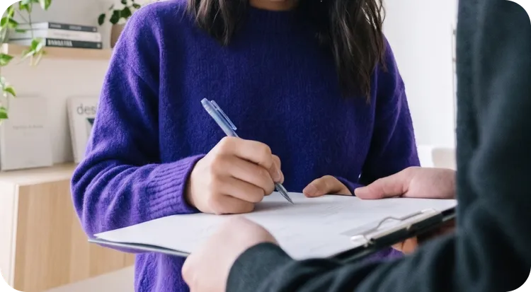 Woman signing documents at a meeting table.