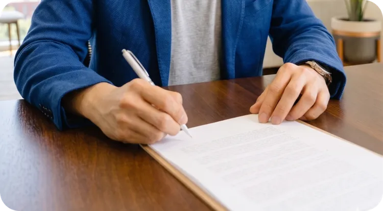 Person making a handwritten signature on a physical contract.