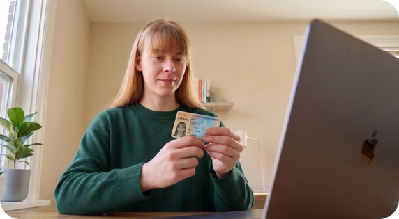 Girl holding an ID card in her hands in front of a computer.