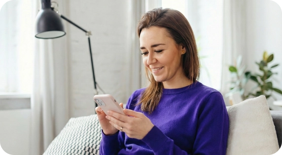 Close-up of a young woman looking at her phone while holding an ID card in the foreground, in a bright and modern indoor setting.