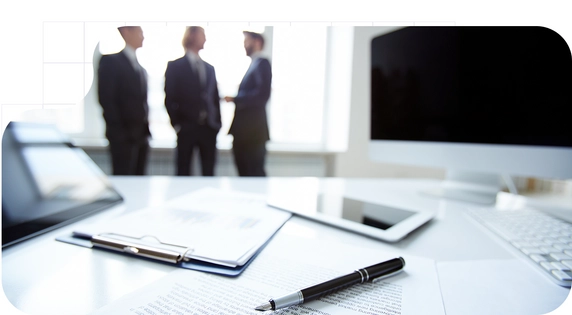 Tres hombres hablando cerca de una mesa con papeles sobre la CDD.