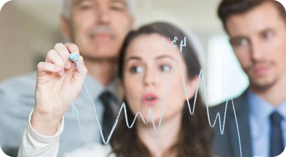 Team of professionals analyzing sales trends on a whiteboard.